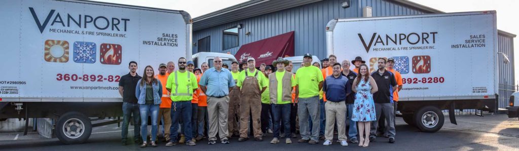 Vanport Mechanical group photo in front of buildings and trucks