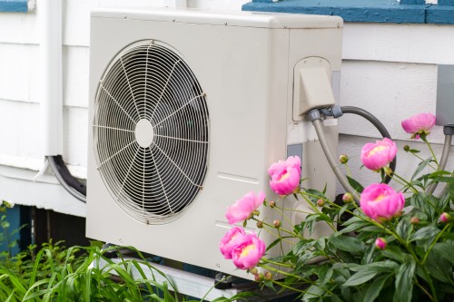 Heat pump in yard with flowers