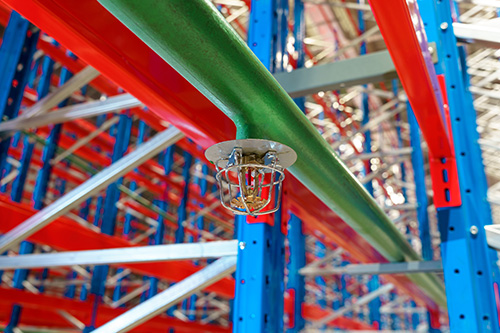 Fire sprinkler in a large warehouse with metal shelving