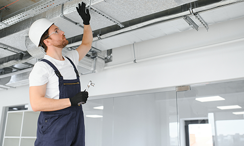 Commercial heating and cooling technician performs maintenance after estimating commercial hvac retrofit costs