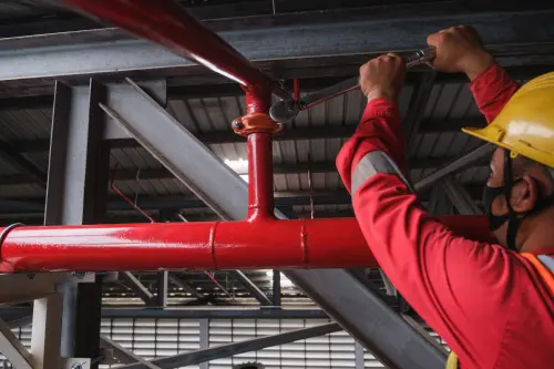 Closeup of a Contractor Installing a Fire Sprinkler System. In the Industrial Plant, Pipe Assembly, Red Fire Pipe, Fire Protection Contractors in Vancouver WA and Portland OR Metro Area