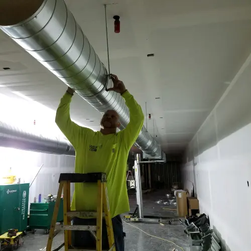 A Vanport Mechanical & Fire Sprinkler technician installing new HVAC ventilation ducting